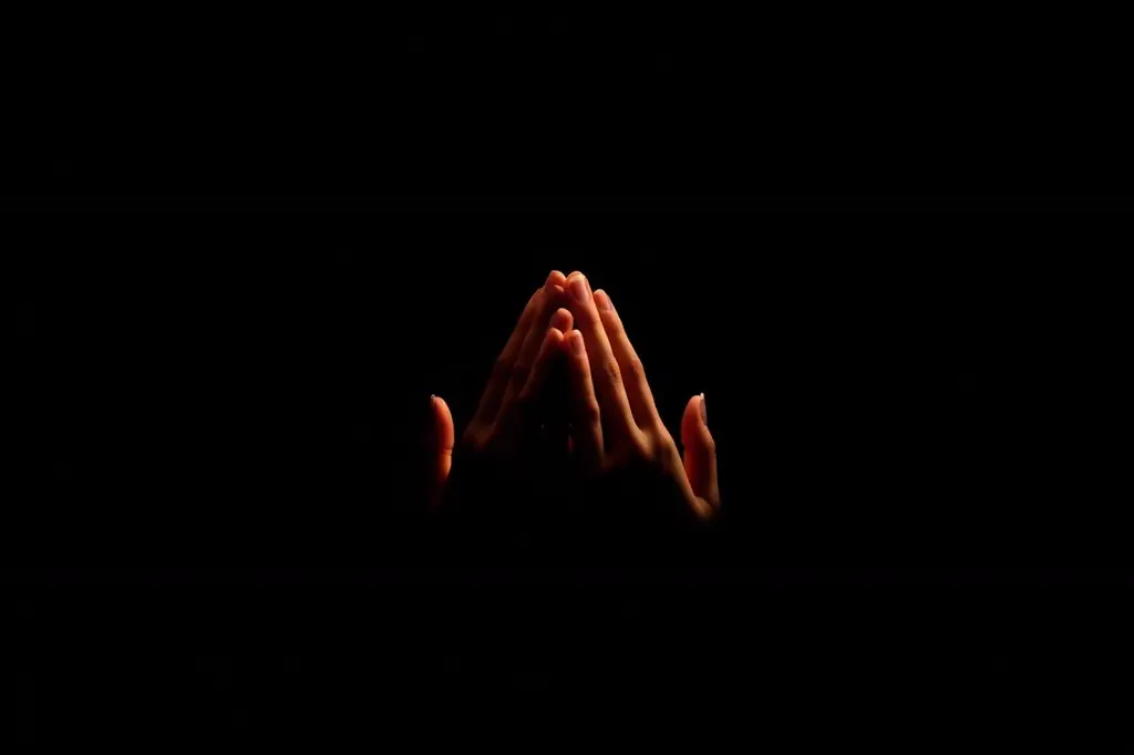 Mãos unidas em gesto de recolhimento sob luz âmbar suave